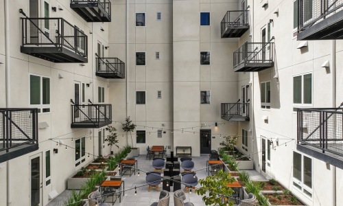 Rooftop greenspace with tables and chairs and many trees and plants